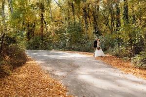 caminhada da noiva e do noivo pela floresta de outono foto