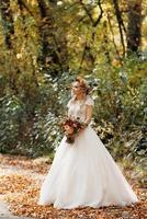 menina loira com um vestido de noiva na floresta de outono