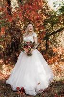menina loira com um vestido de noiva na floresta de outono