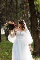 garota em um vestido de noiva na floresta de outono foto