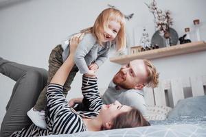 família feliz junta. filha mãe, pai e filho se abraçando no quarto em dia festivo foto