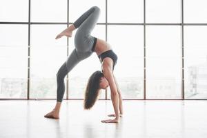 uma esportista que está fazendo aulas de ioga, esticando as pernas perto da grande janela foto