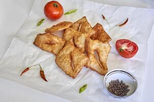 frito pastelaria em papel com tomates e especiarias foto