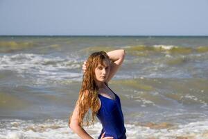 uma Loiras menina dentro uma azul tomando banho terno em a de praia. de praia feriados. foto