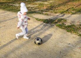 a criança é jogando com a bola. uma pequeno criança de quatro anos menina tocam com uma futebol. foto