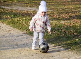 a criança é jogando com a bola. uma pequeno criança de quatro anos menina tocam com uma futebol. foto