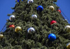 decorações Novo ano árvore. ouropel e brinquedos, bolas e de outros decorações em a Natal Natal árvore em pé dentro a aberto ar. foto