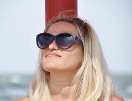 a Loiras dentro oculos de sol em a de praia. menina em repouso em a de praia foto