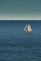 Mônaco, solitário vintage vela iate dentro mar às pôr do sol, enorme vela barco, riqueza vida do bilionários foto
