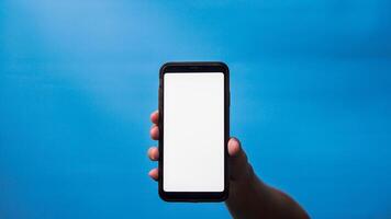 mão do homem segurando Móvel Smartphone e mostrando em branco telefone tela em azul fundo foto