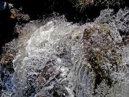 cascata a partir de a descongelado águas. Derretendo neve dentro a montanhoso fundo foto