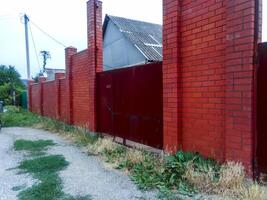 aço oxidado portões e uma vermelho tijolo cerca. foto