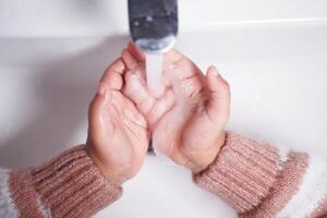 criança lavando as mãos com sabão foto