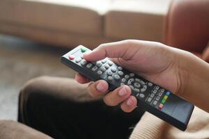 close-up da mão de mulheres segurando o controle remoto da tv. foto