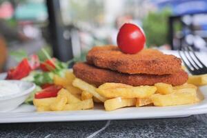 frango schnitzel servido com batata salgadinhos foto