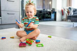 pequeno menina jogando colorida magnético plástico blocos kit às lar. a criança jogando educacional jogos. cedo infância desenvolvimento. foto