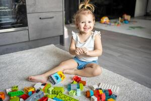 caucasiano criança uma pequeno menina é jogando dentro a construtor às lar. educacional brinquedos para crianças. foto