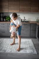 uma feliz pai e pequeno menina alegremente gastos Tempo dentro uma moderno cozinha. feliz família. do pai dia. foto