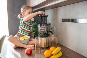 pequeno menina fazer fresco suco sentado em a mesa dentro casa cozinha foto