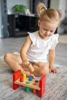 fofa caucasiano pequeno menina jogando em a chão às casa com eco de madeira brinquedos. montessori brinquedo. a criança jogando educacional jogos. foto