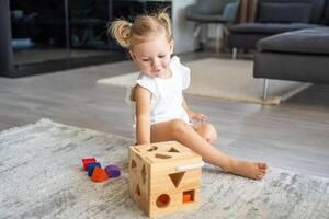 fofa caucasiano pequeno menina jogando em a chão às casa com eco de madeira brinquedos. montessori brinquedo. a criança jogando educacional jogos. foto