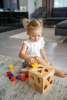 fofa caucasiano pequeno menina jogando em a chão às casa com eco de madeira brinquedos. montessori brinquedo. a criança jogando educacional jogos. foto