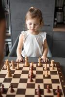 pai ensino dele pequeno filha para jogar xadrez às a mesa dentro casa cozinha. a conceito cedo infância desenvolvimento e Educação. família lazer, comunicação e lazer. foto