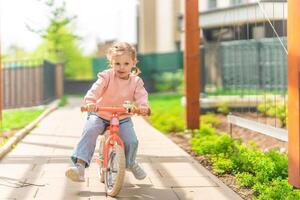 pequeno menina equitação Saldo bicicleta dentro a pátio do a residência dentro Praga, Europa foto