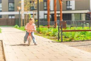 pequeno menina equitação Saldo bicicleta dentro a pátio do a residência dentro Praga, Europa foto