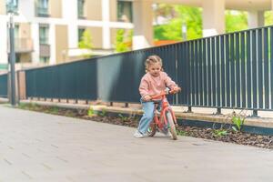 pequeno menina equitação Saldo bicicleta dentro a pátio do a residência dentro Praga, Europa foto