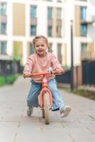 pequeno menina equitação Saldo bicicleta dentro a pátio do a residência dentro Praga, Europa foto