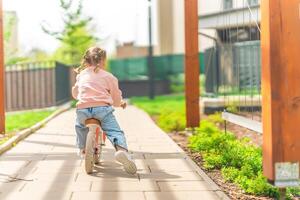 pequeno menina equitação Saldo bicicleta dentro a pátio do a residência dentro Praga, Europa foto