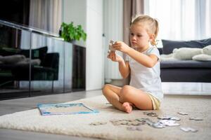 pequeno Loiras menina senta às casa em a tapete e coleta quebra-cabeças foto
