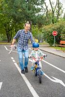 feliz jovem pai ensina criança filha para passeio público bicicleta em 1 do tráfego Parque infantil dentro Praga, tcheco república, Europa foto