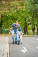 pai ensina criança filha para passeio público bicicleta em tráfego Parque infantil dentro Praga, tcheco república foto