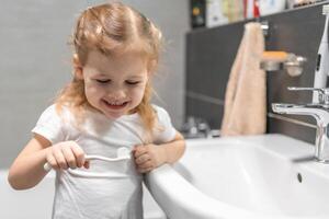 feliz criança pequena menina escovar dentes dentro a banho foto
