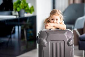 pequeno menina com mala de viagem Bagagem bagagem pronto para ir para viajando em período de férias foto