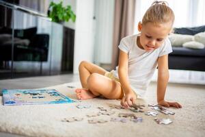 pequeno Loiras menina senta às casa em a tapete e coleta quebra-cabeças foto
