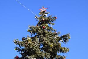 decorações Novo ano árvore. ouropel e brinquedos, bolas e de outros decorações em a Natal Natal árvore em pé dentro a aberto ar. foto