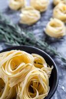 cru tagliatelle nido em a polvilhado com farinha Preto de madeira fundo foto