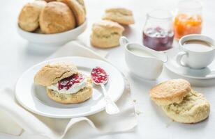 scones com creme e fruta geléia e copo do café foto