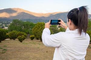 latim mulher usando dela célula telefone dentro uma parque. foto