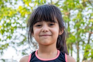 fechar-se retrato do dela. ela é amigável, encantador, doce, curioso e alegre. pequeno menina ao ar livre dentro Esportes roupas. foto