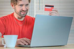 retrato do uma homem compras conectados com uma crédito cartão. foto