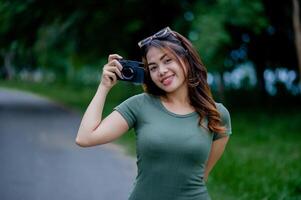 lindo ásia turista e dela pessoal Câmera fêmea fotógrafo cercar milésimos foto