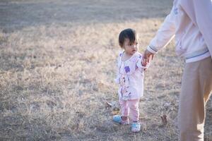 mãe e filha jogando e corrida por aí a parque em lindo manhã. foto