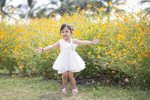 uma feliz jovem menina admira e suavemente toques e admira uma florescendo flor. isto reflete a beleza do Primavera e a simples prazeres do ser dentro contato com natureza. Primavera despertar. foto