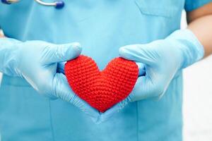 médico de mulher asiática segurando coração vermelho para saúde no hospital. foto