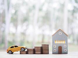 miniatura casa e de madeira brinquedo carro em pilha do moedas. a conceito do salvando dinheiro para carro e casa foto