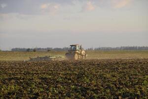 trator aração arado a campo. lavrando a solo dentro a outono depois de colheita. a fim do a estação foto